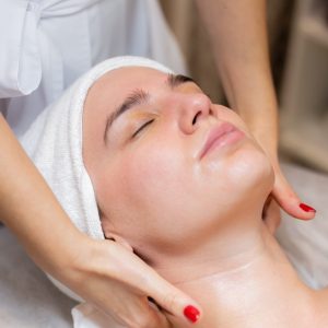 A young beautiful girl lies on the beautician's table and receives procedures, a light facial massage using oil. Woman takes care of herself, enjoys massage
